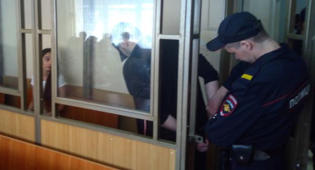 Суд по делу обманутых дольщиков в Ростове-на-Дону: конвой снимает наручники с Артура Попова, за стеклом Елена Домась. Фото Константина Волгина для "Кавказского узла"
