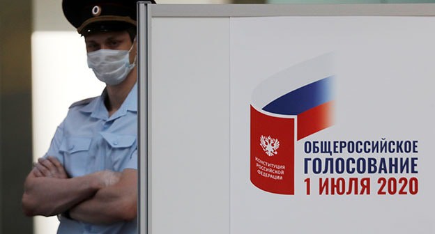Сотрудник правоохранительных органов рядом с плакатом. Фото: REUTERS/Anton Vaganov
