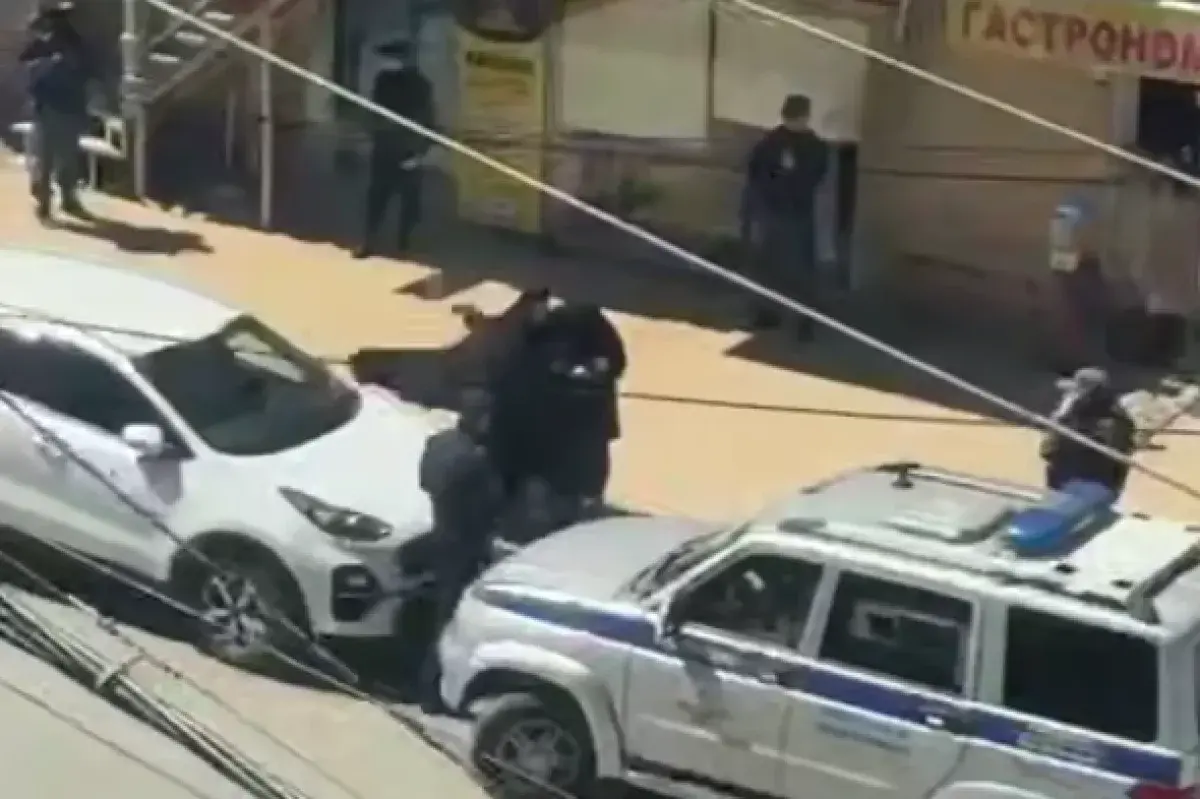 Силовик сажает мусульманку в машину. Стоп-кадр видео из Telegram-канала "Совесть Дагестана" от 20.04.25, https://t.me/sovestdagestana/38592