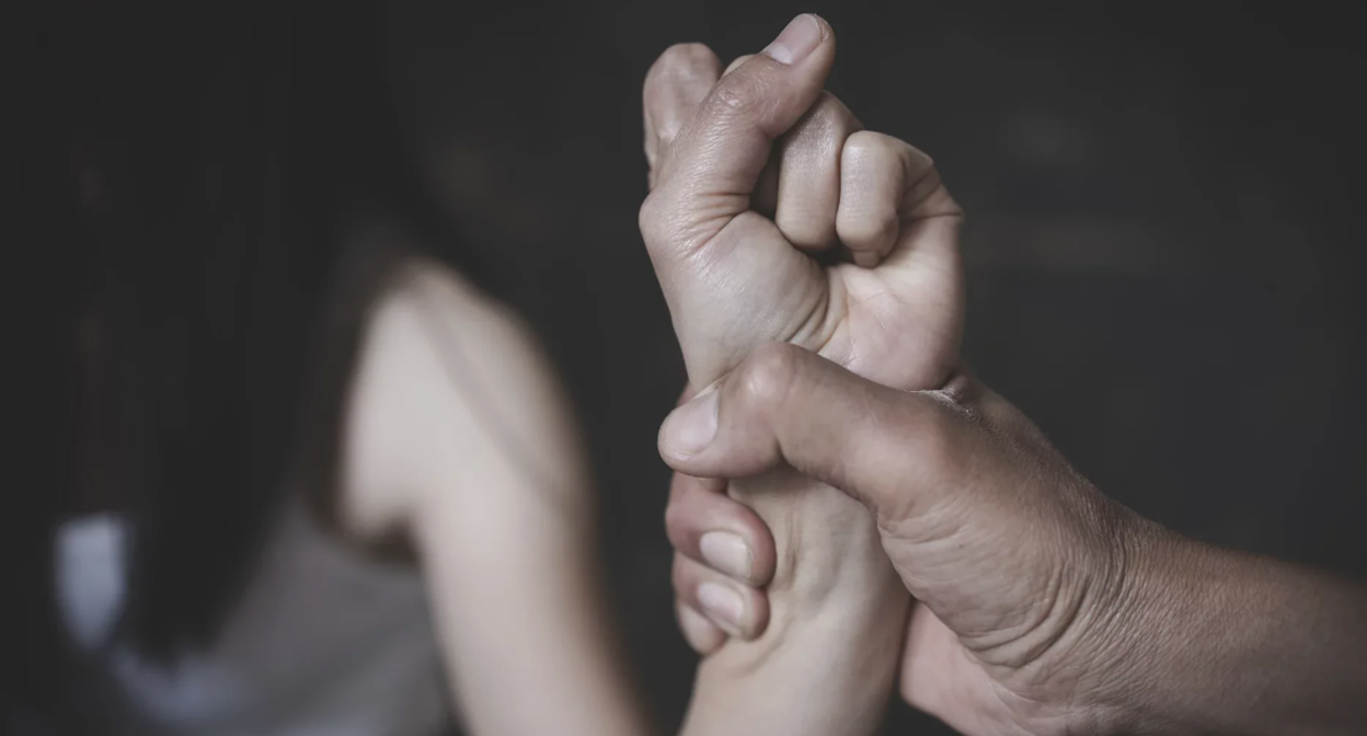 Мужчина держит руку женщины. Скриншот фото с сайта https://nso.gov.mt/crime/domestic-violence-2023/.