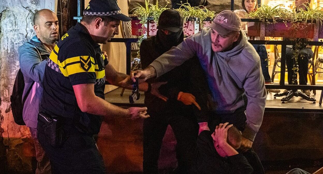 Леван Джобава (в сером свитшоте и бейсболке) передает патрульному пистолет нападавшего (держит руки за головой), 15 сентября 2025 года. Фото: Мариам Кавшбая / Publika 