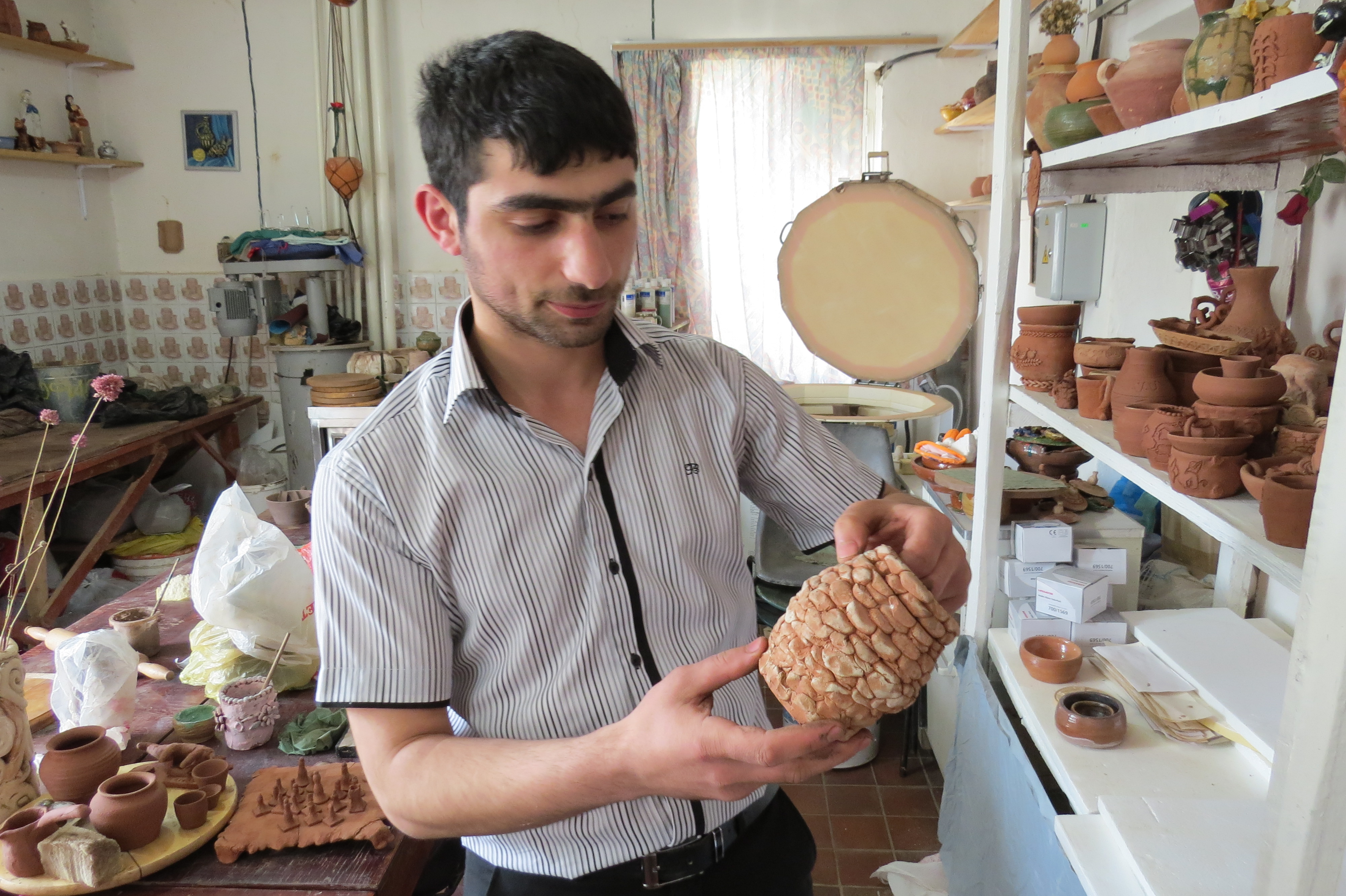 Сероб показывает одну из работ малышей, которые самостоятельно вылепили их кружочков стену небольшой чаши 