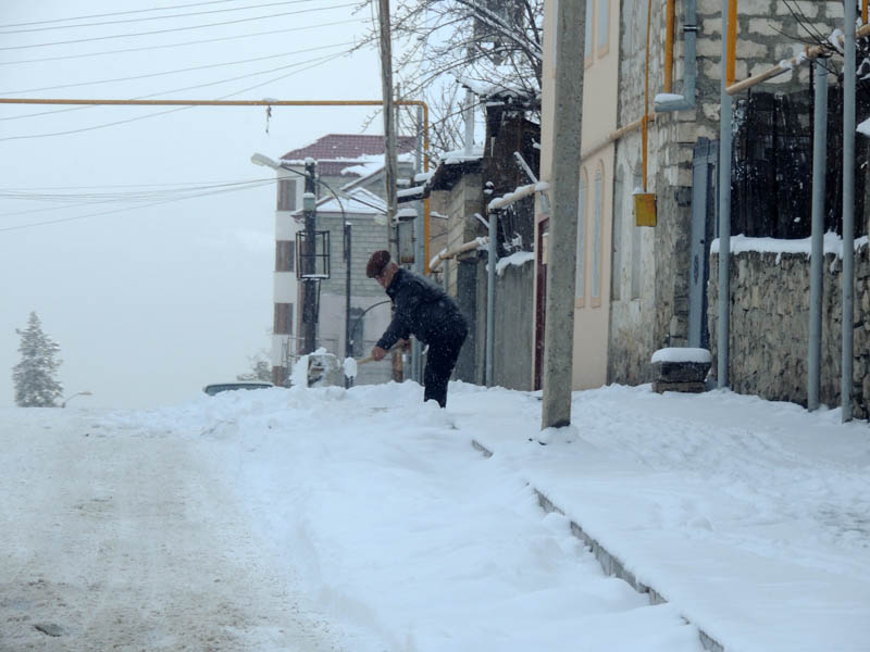 Мужчина очищает территорию перед своим домом.