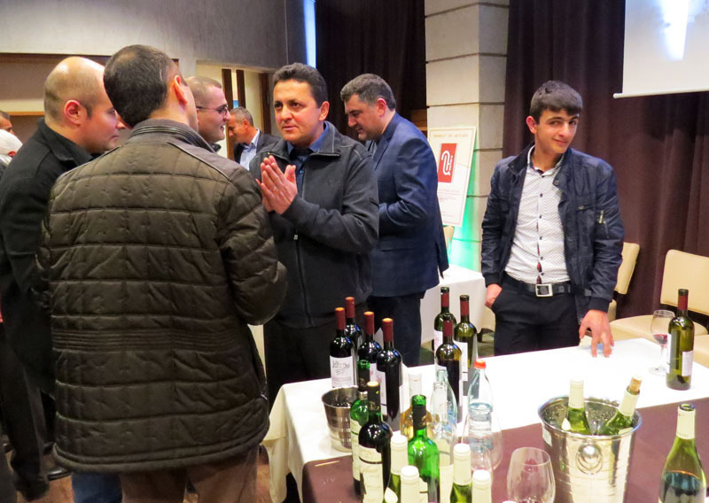 Производитель вина Мельсик Саркисян (Степанаекрт) рядом со столиком, где выставлено изготовленное им вино.