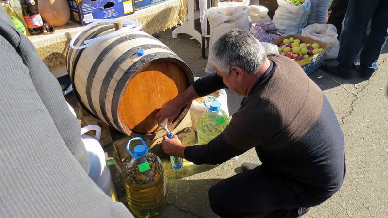  Хозяин тутовки наливает бутылочку для клиента.