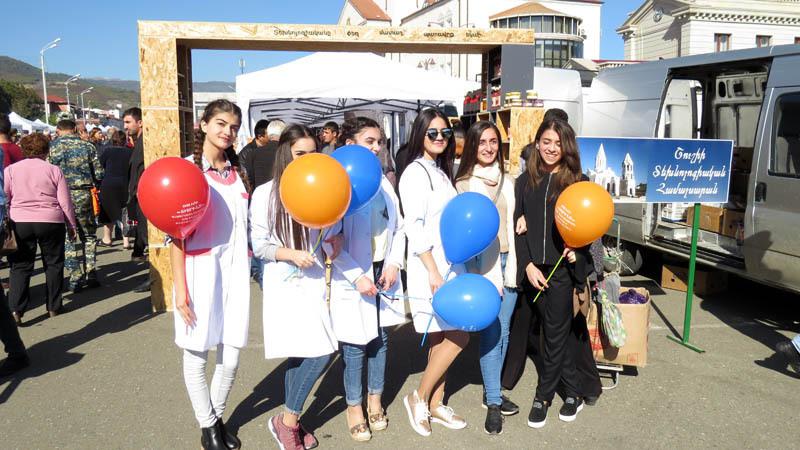 Девушки одеты в белые халатики. Это означает, что вся продукция на ярмарке экологически чистая.